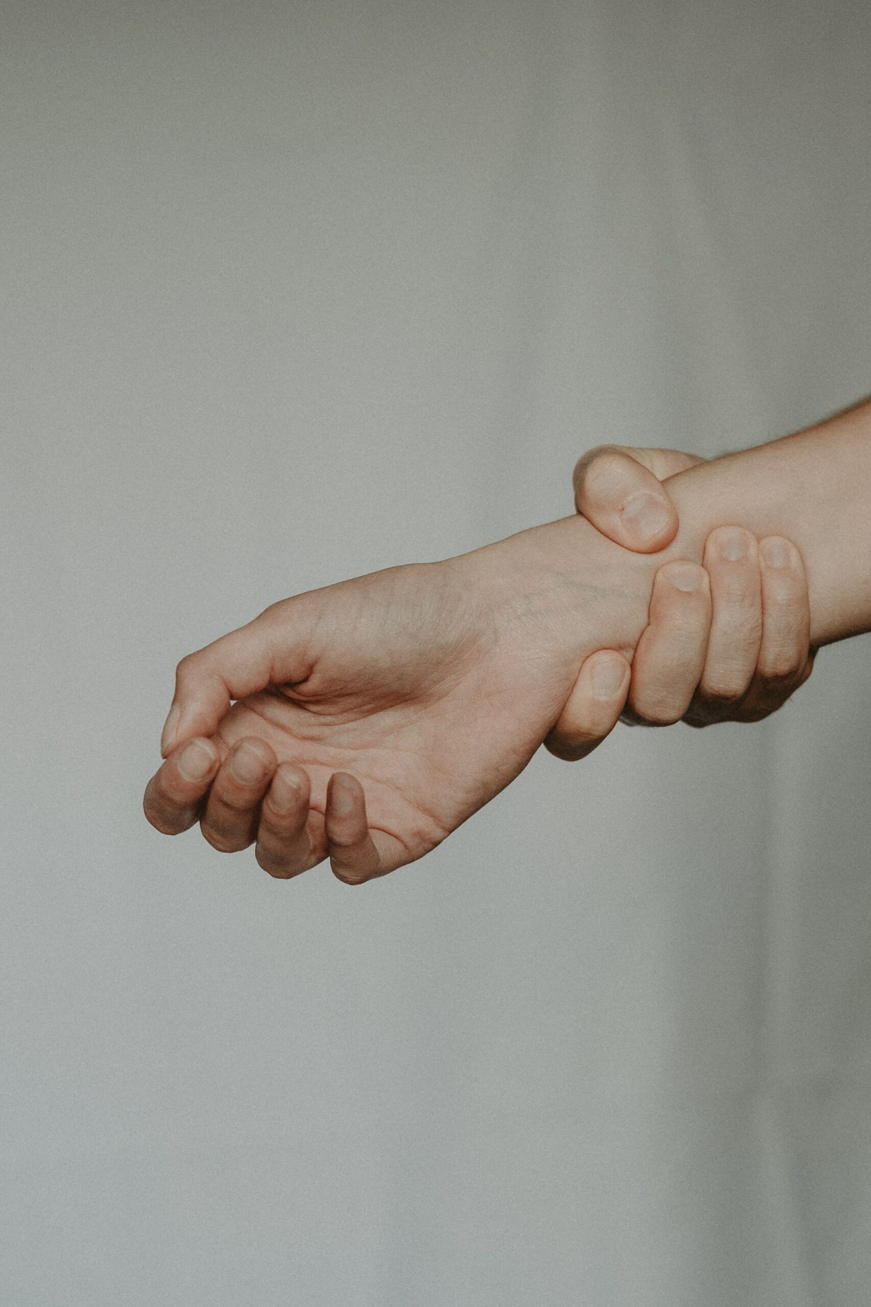 A person's hand with another hand around their wrist