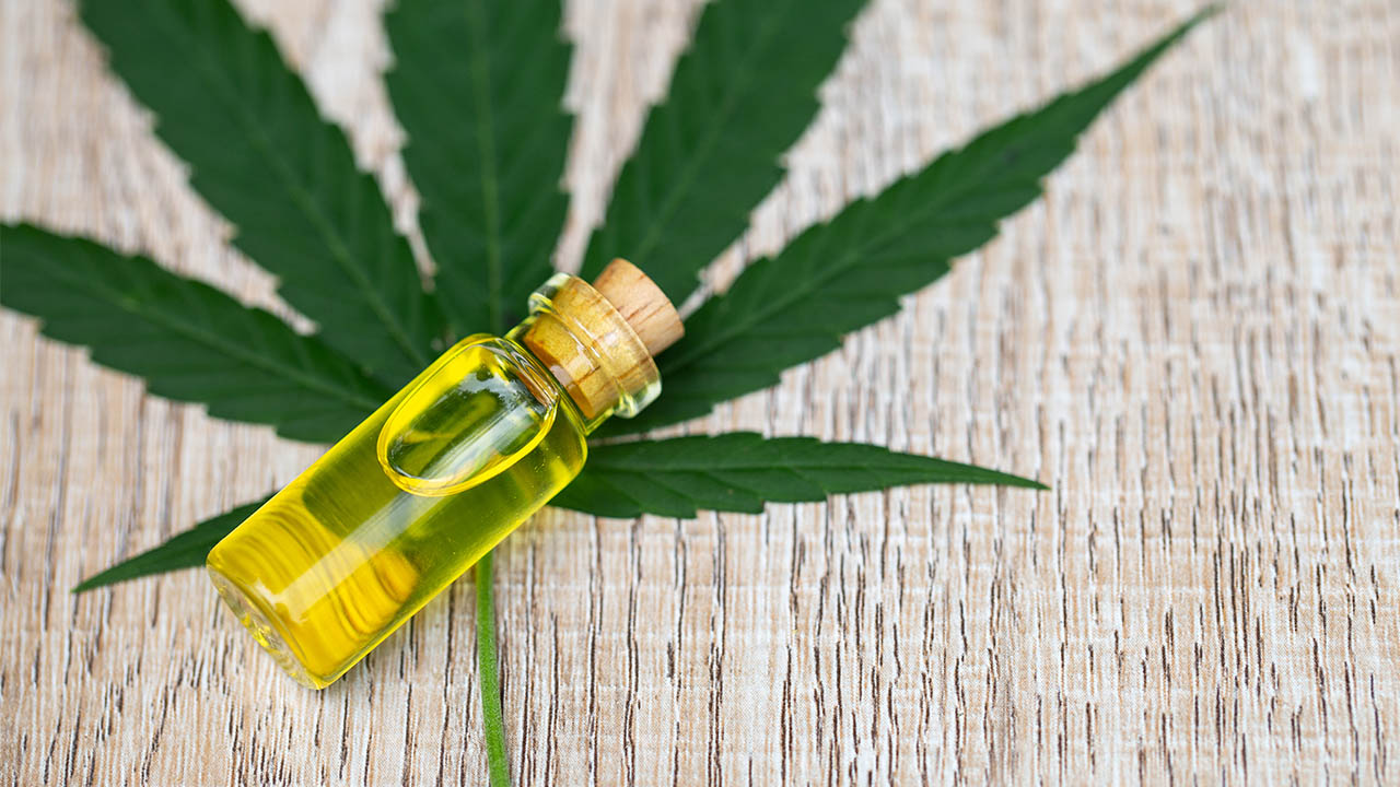 A CBD bottle on top of a cannabis leaf