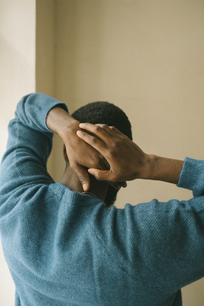 A man facing away with his hands on the back of his head