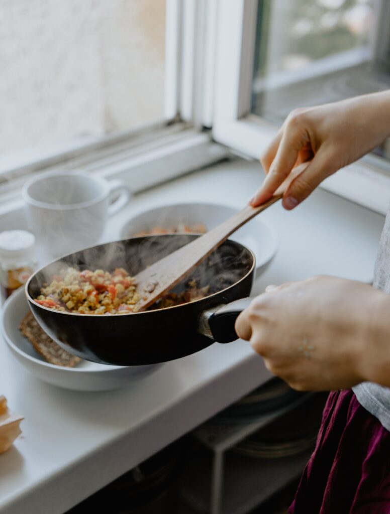 A person serving up a healthy meal from a pan into two bowls