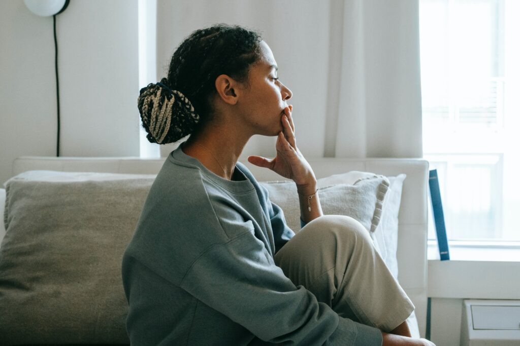 A woman sitting on a bed looking pensive