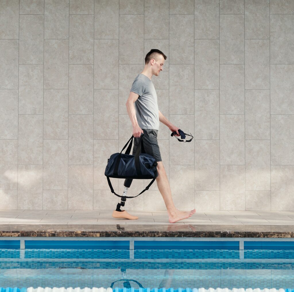 A man with a prosthetic leg walking along the edge of a pool