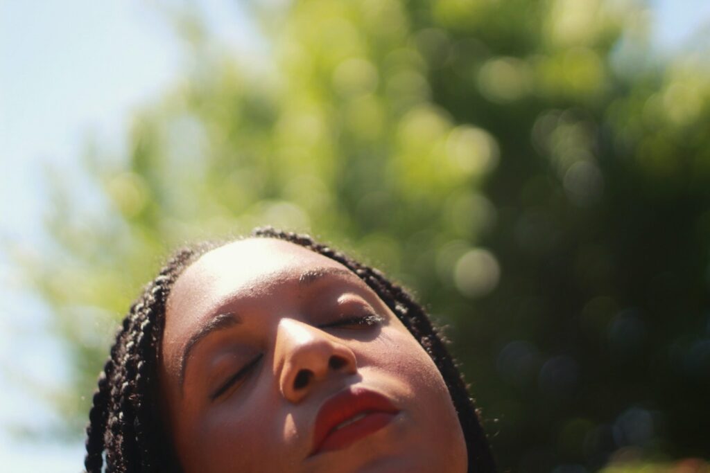 A woman with closed eyes looking up to the sun