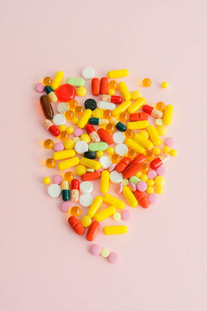 An assortment of yellow, pink, white, and red medication, such as pills and capsules