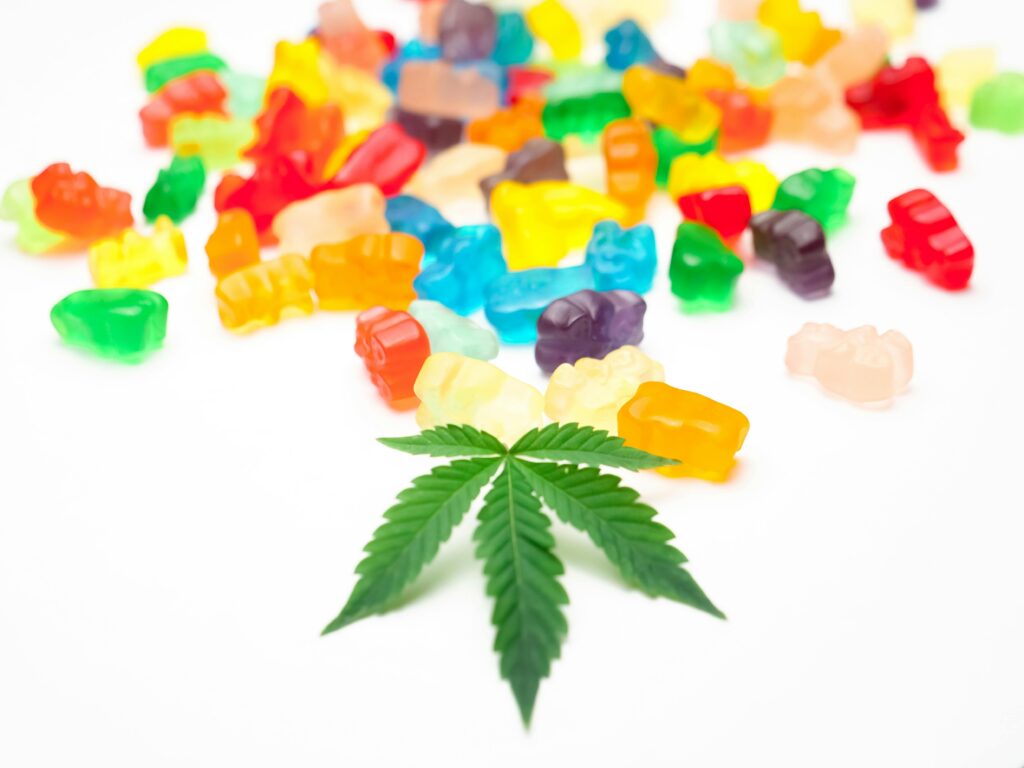 Medical cannabis gummies of various colours with a cannabis leaf in the foreground