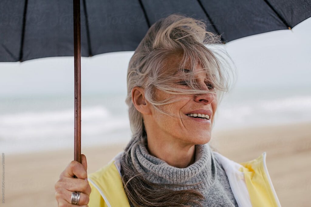 A woman on the beach holding up an umbrella