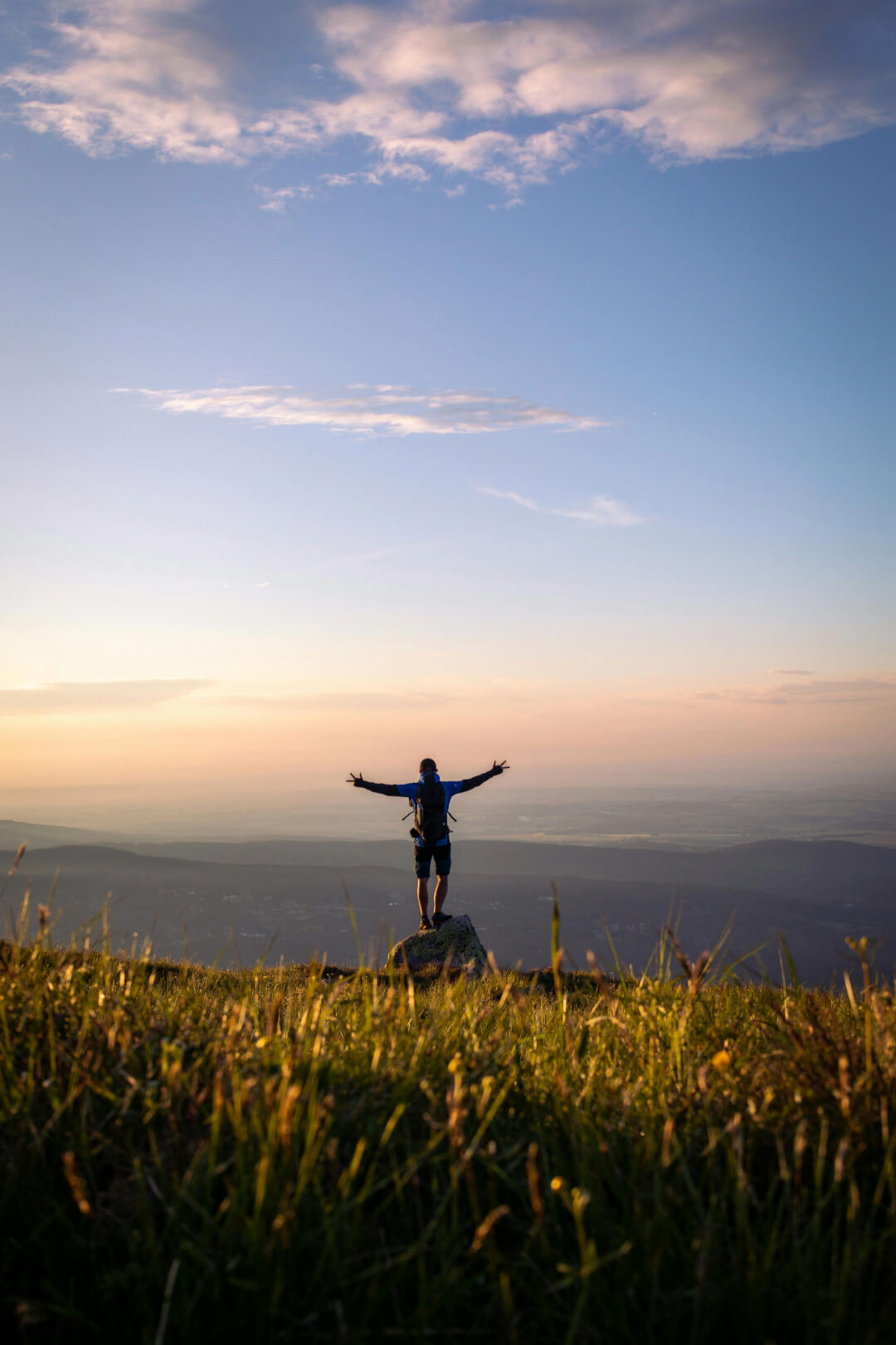 A person standing with their arms outstretched admiring the landsccape