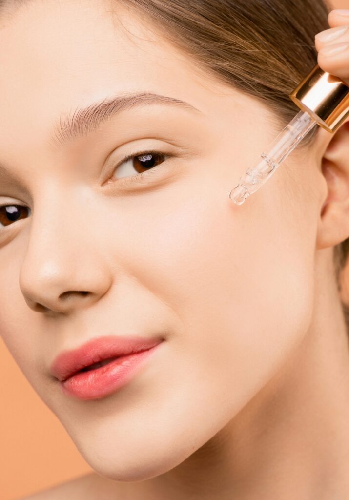 A woman uses a CBD dropper on her cheek