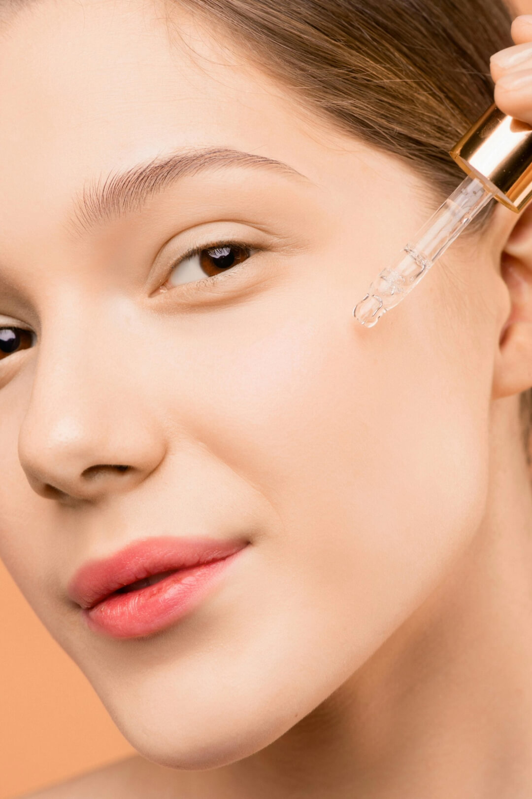 A woman using a CBD dropper on her cheek