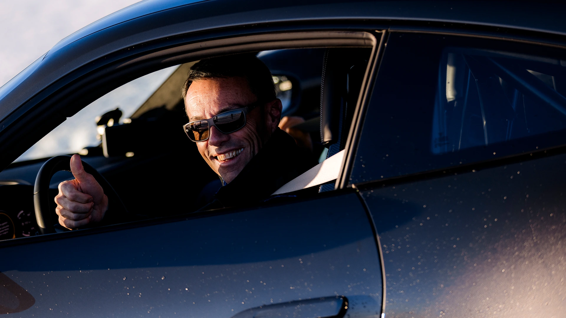 Begeisterter Trackday-Teilnehmer zeigt Daumen hoch aus dem Porsche-Cockpit nach erfolgreicher Runde