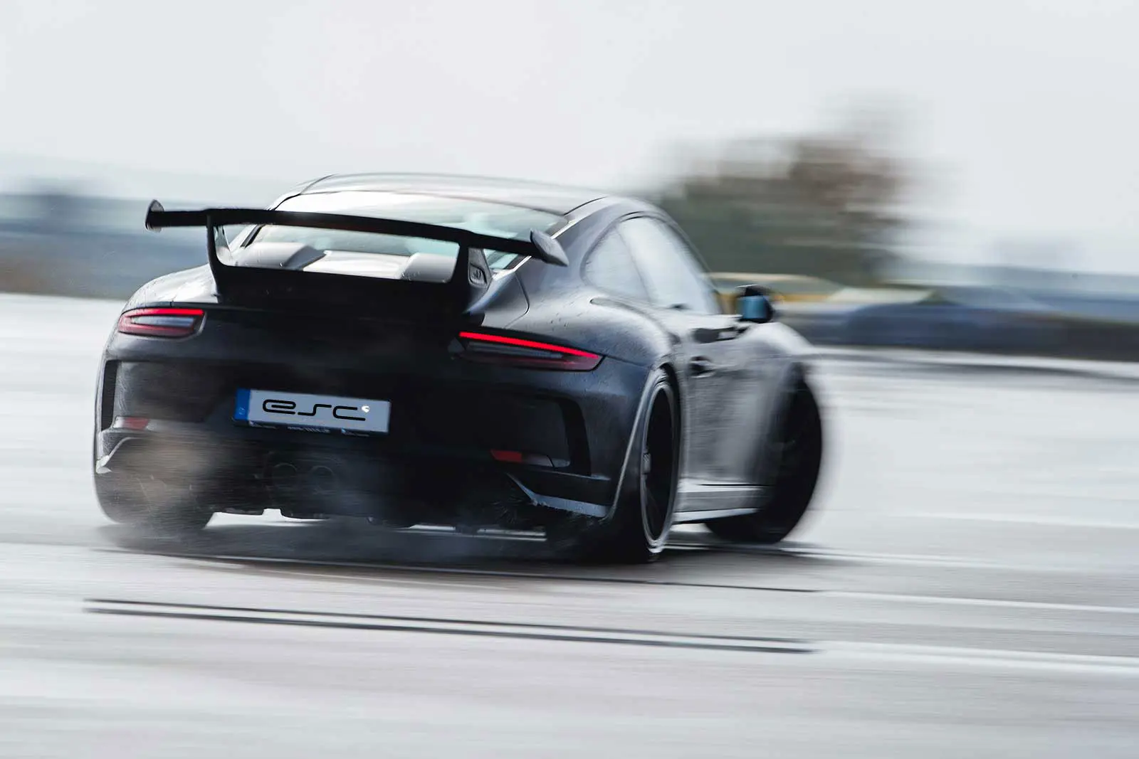 ESC Trackday buchen – Schwarzer Porsche GT3 bei Highspeed auf nasser Strecke von hinten mit ESC Kennzeichen
