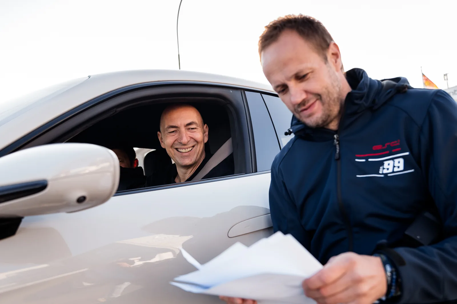 ESC coach discussing the racing line with a driver in a white Porsche in the Nürburgring pit lane