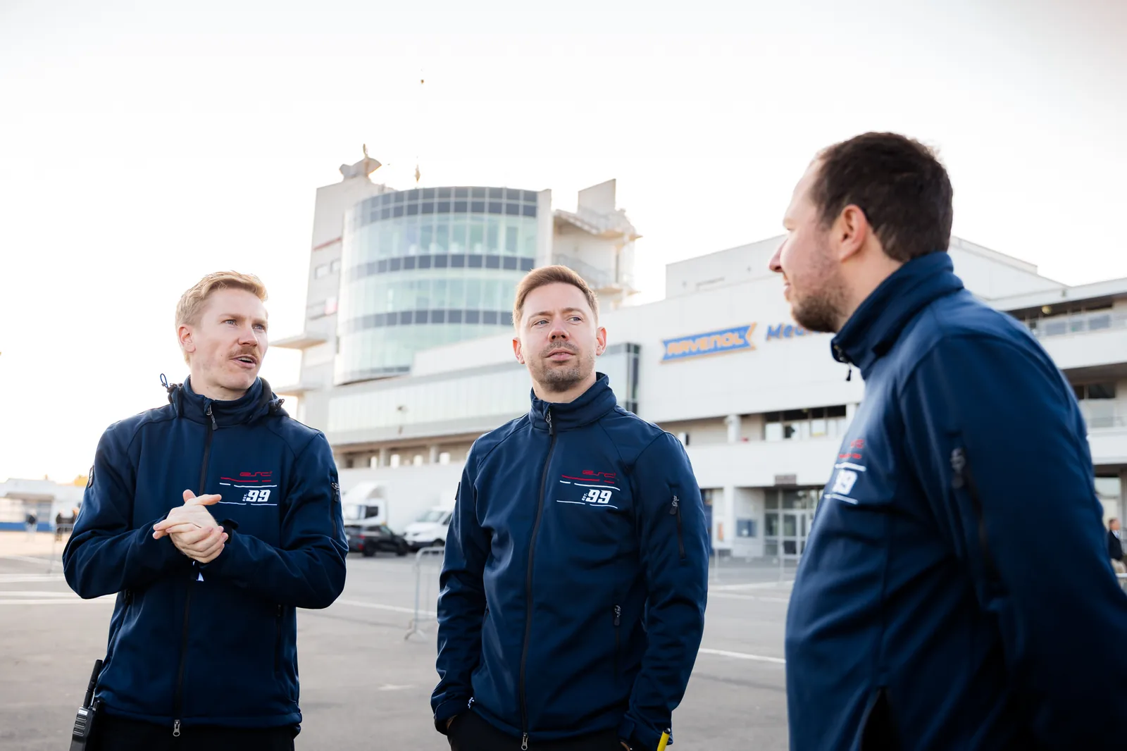 Three ESC coaches in conversation in front of the Nürburgring paddock during the track day