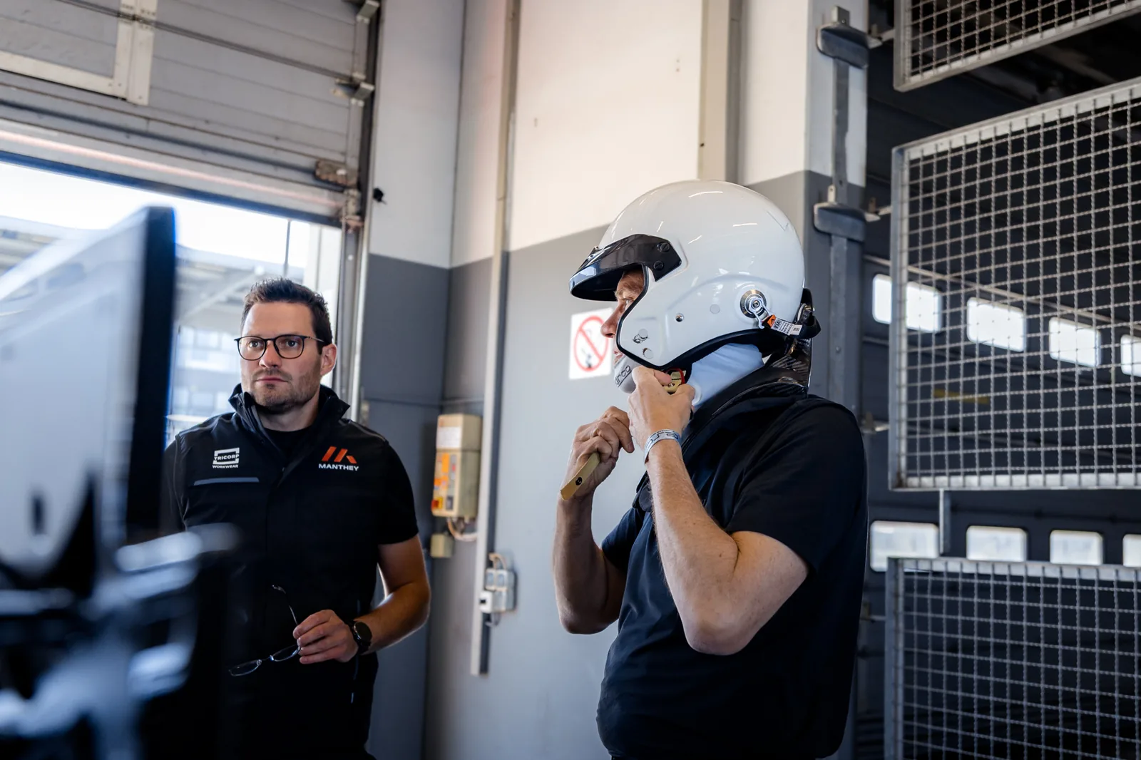 Manthey expert advising a driver in a racing helmet on Porsche GT3 RS setup in the pit lane at the ESC track day