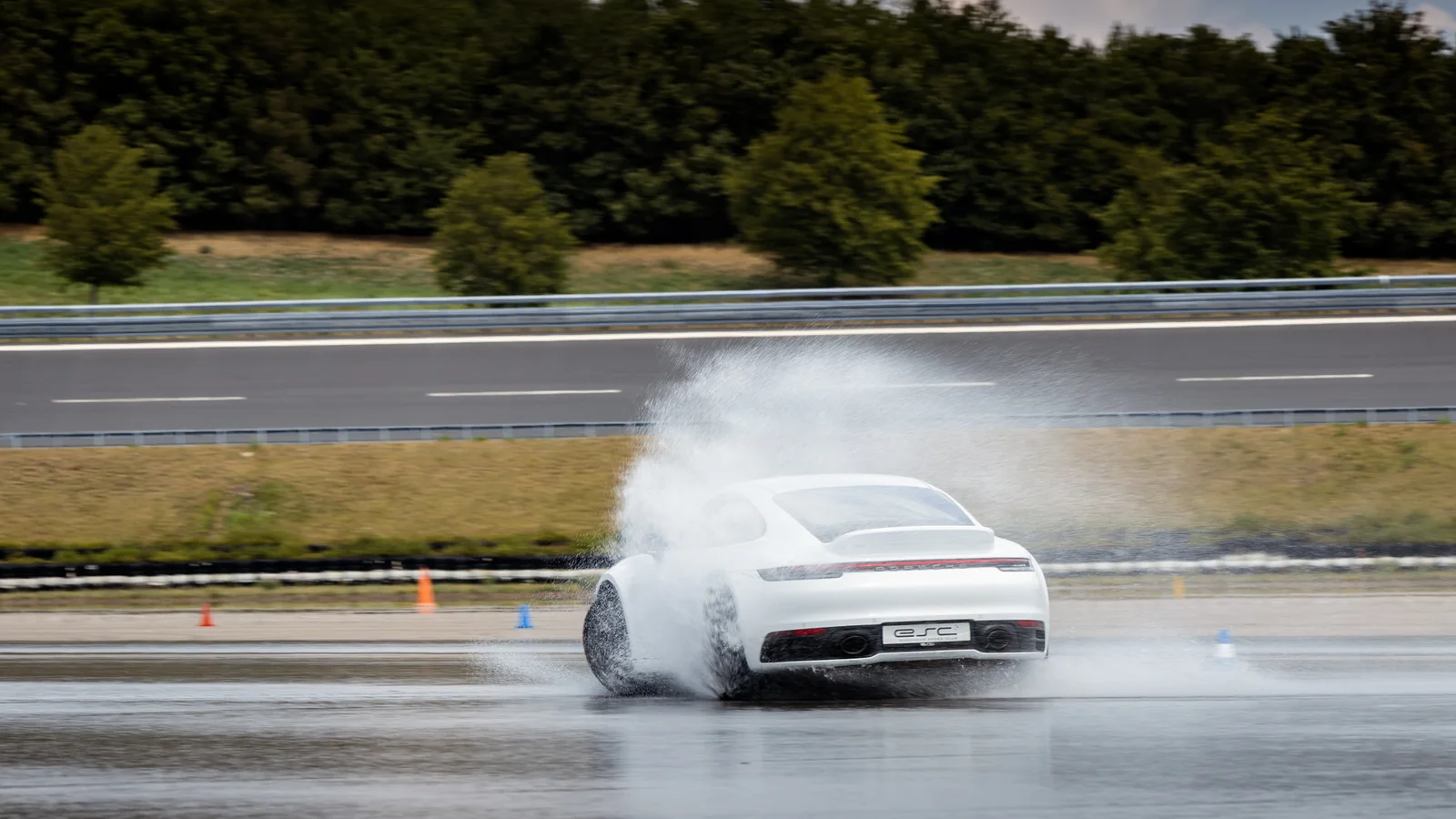 Porsche 911 driftet mit Gischt über die bewässerte Fläche in Boxberg