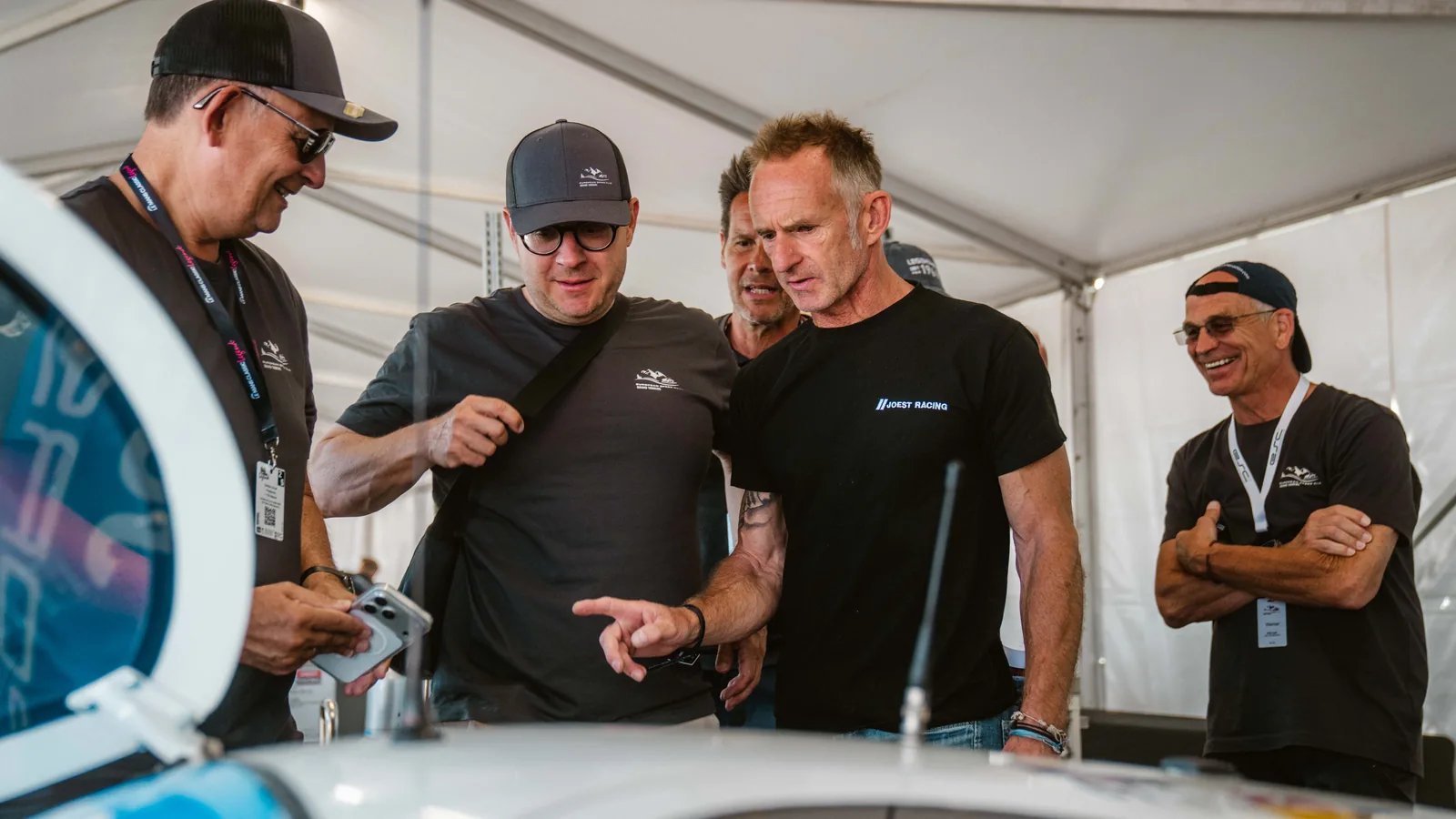 Teilnehmer im Fahrerlager der Le Mans Classic im Gespräch an einem historischen Rennwagen