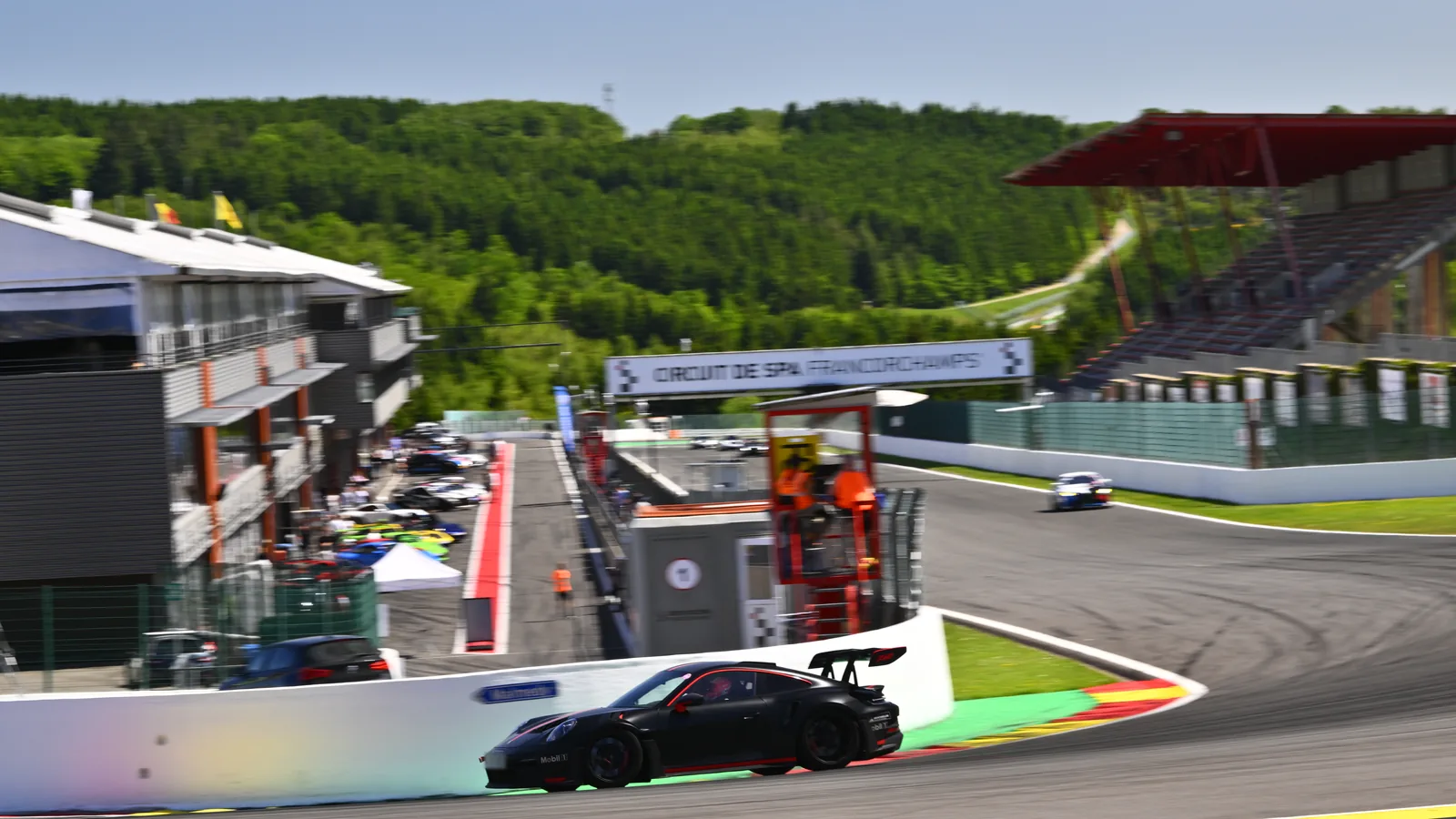 Boxenanlage und Streckenverlauf in Spa-Francorchamps mit Sportwagen und Ardennen-Kulisse