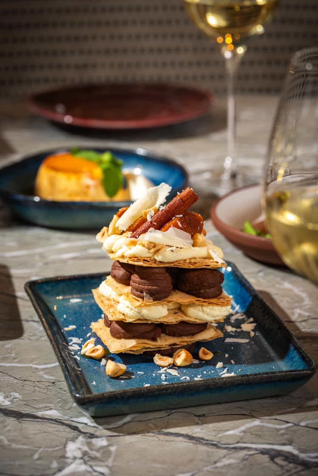 Calamari and pulled beef sandwich with pickled red peppers, served with mixed greens on a sunlit outdoor table
