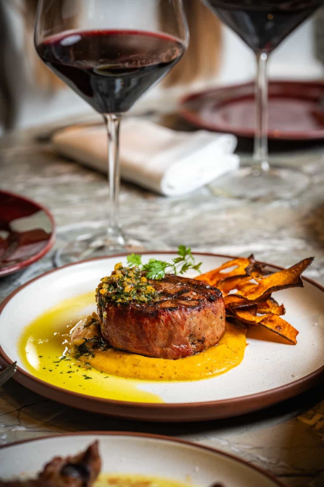 Crispy paella dish with artichokes and beef cheek, served outdoors on a marble table