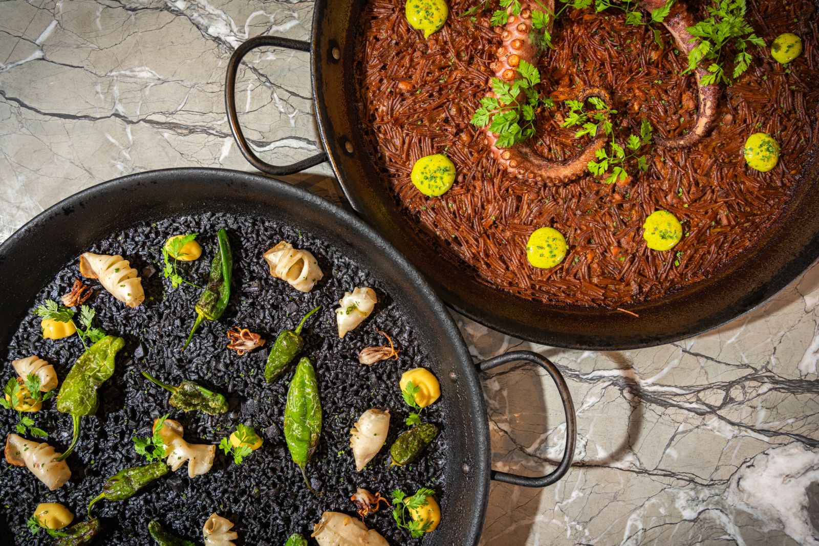 Seafood rice dish with red prawns and mussels, artfully arranged in a paella pan on a marble surface
