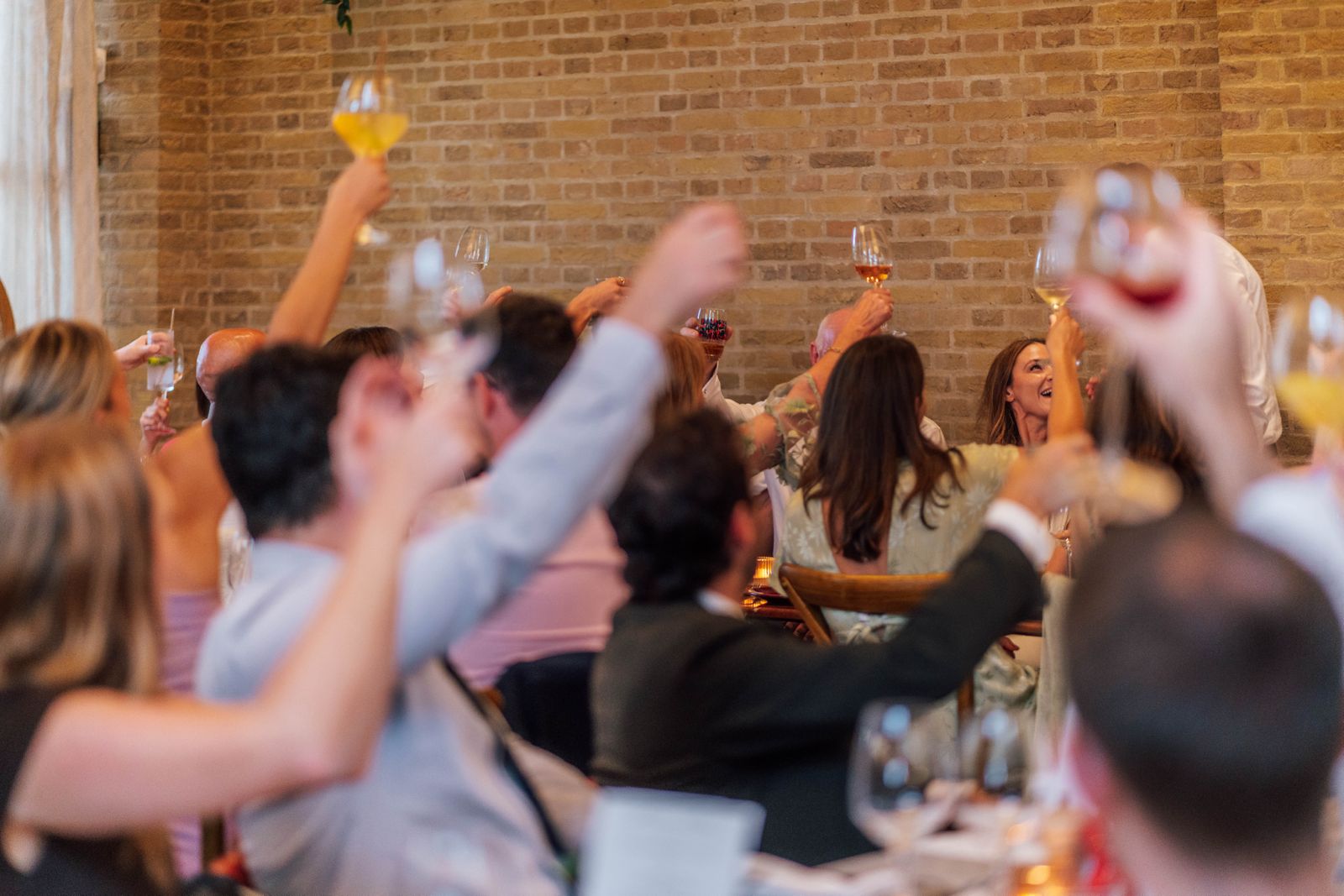 Sunlit indoor dining space with patterned benches, wooden tables, and an olive tree surrounded by lush greenery