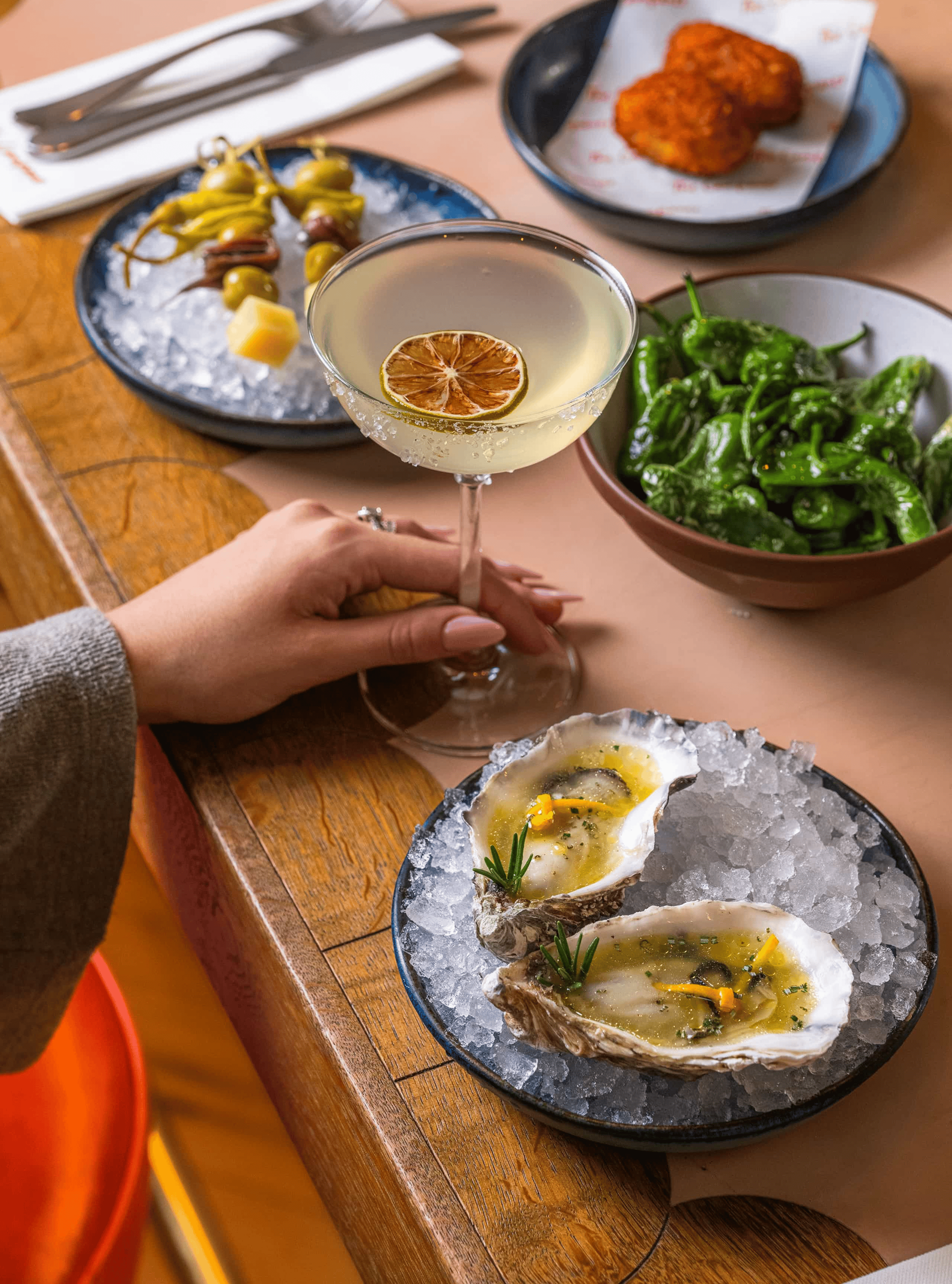Outdoor table setting with a bottle of white wine and two glasses, framed by greenery and a historic brick building in the background