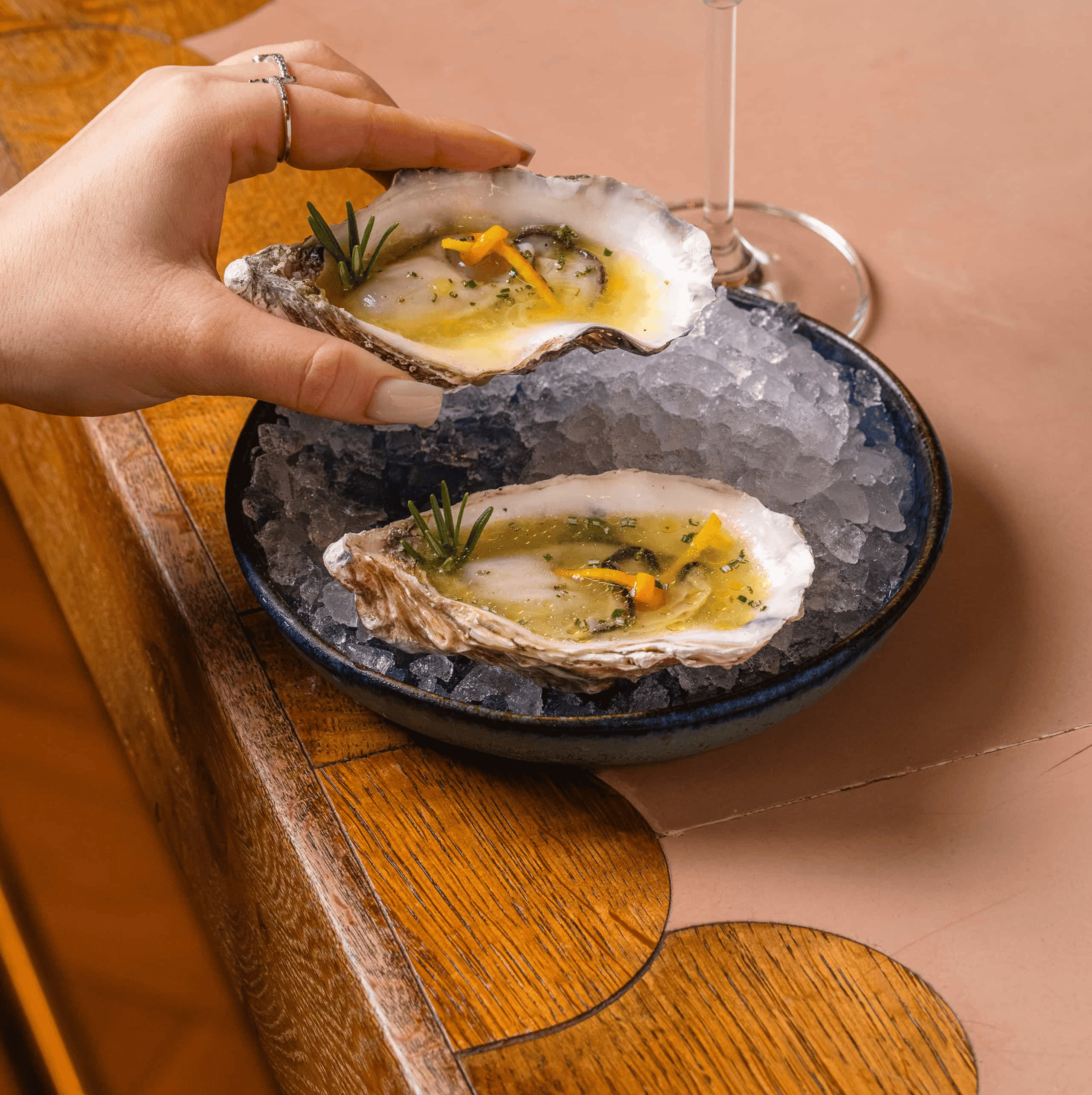 Glass and pitcher of red sangria with citrus slices and ice, next to a small vase with fresh flowers