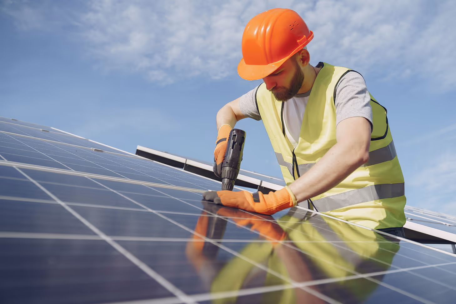 Un homme fixe des panneaux solaires sur le toit d'une maison 