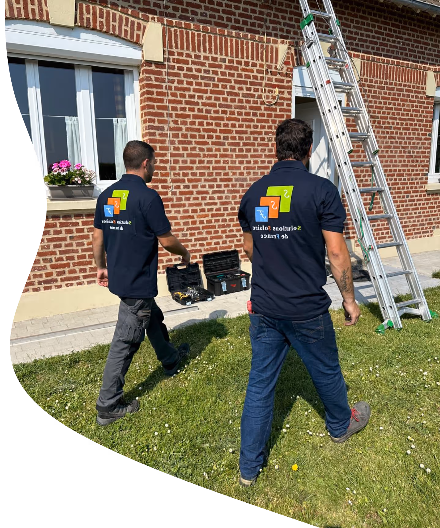 Deux hommes debout sur une échelle devant un bâtiment en briques.