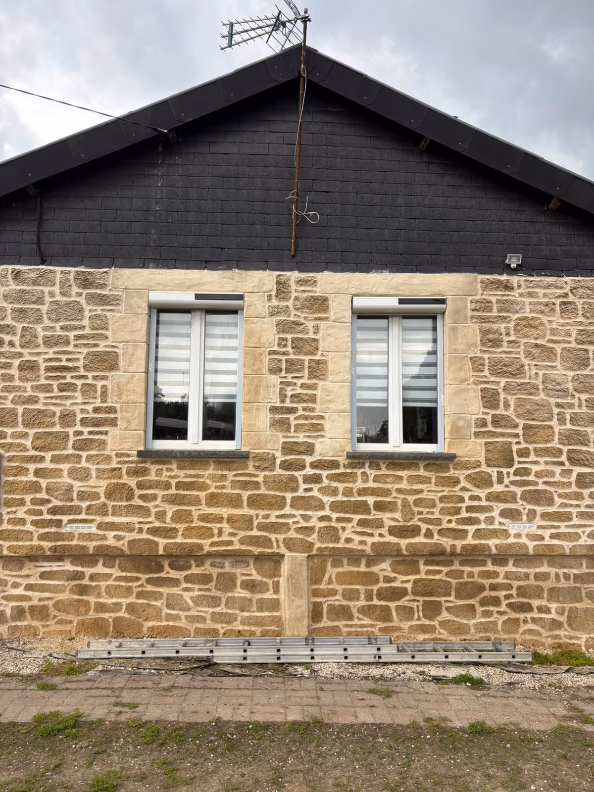 deux petites fenêtres équipée de volets roulants solaires sur un mur en pierre