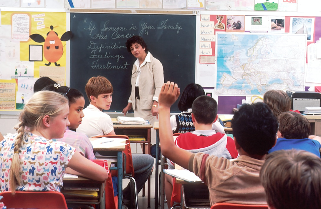 A group of Hollam private students sitting at desks in front of a blackboard.