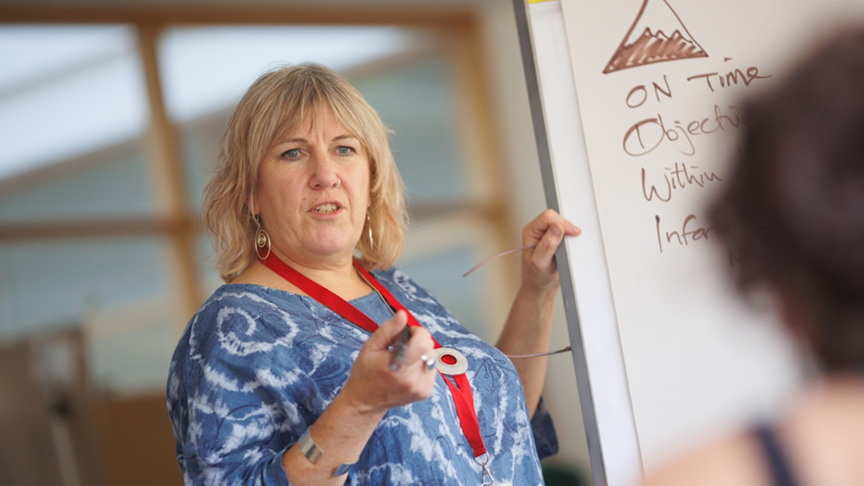 A Hollam private tutor woman standing in front of a white board.
