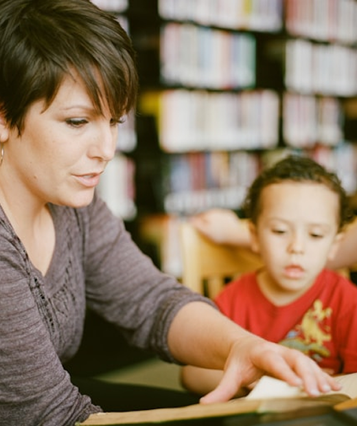 A woman reading a book to a little child.