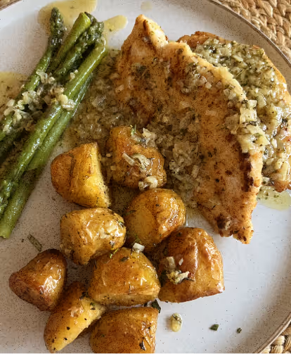 A beautifully cooked chicken breast, potatoes, and asparagus