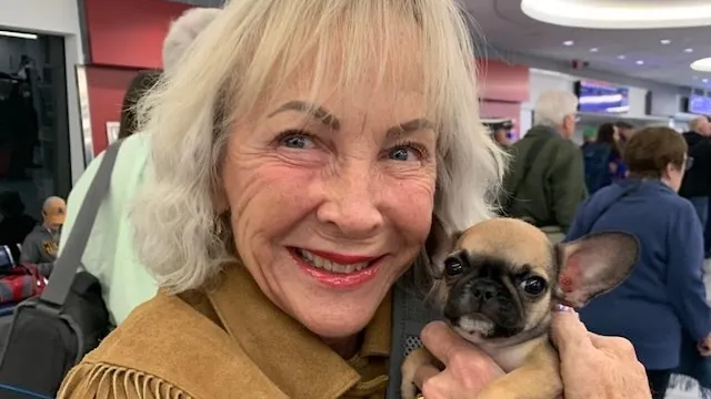 Owner smiling while holding a new tiny Royal Frenchel puppy.