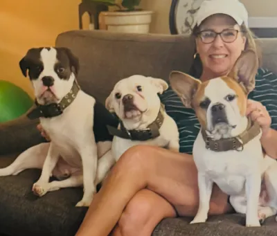 Three Small Royal Frenchels sitting on a couch beside their owner.