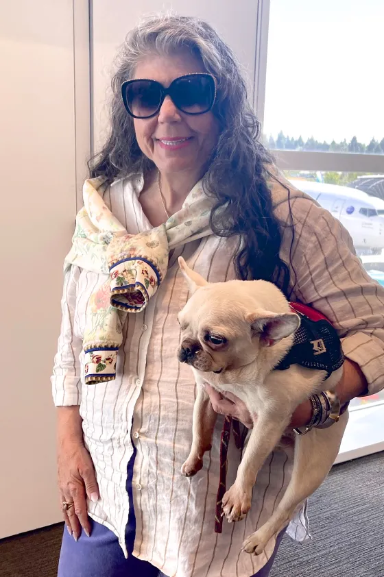 Anahata Graceland sitting in an airport with two Regular Royal Frenchel service dogs.
