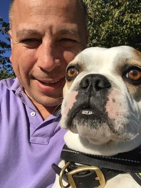 Small Royal Frenchel smiling with its owner in a selfie.