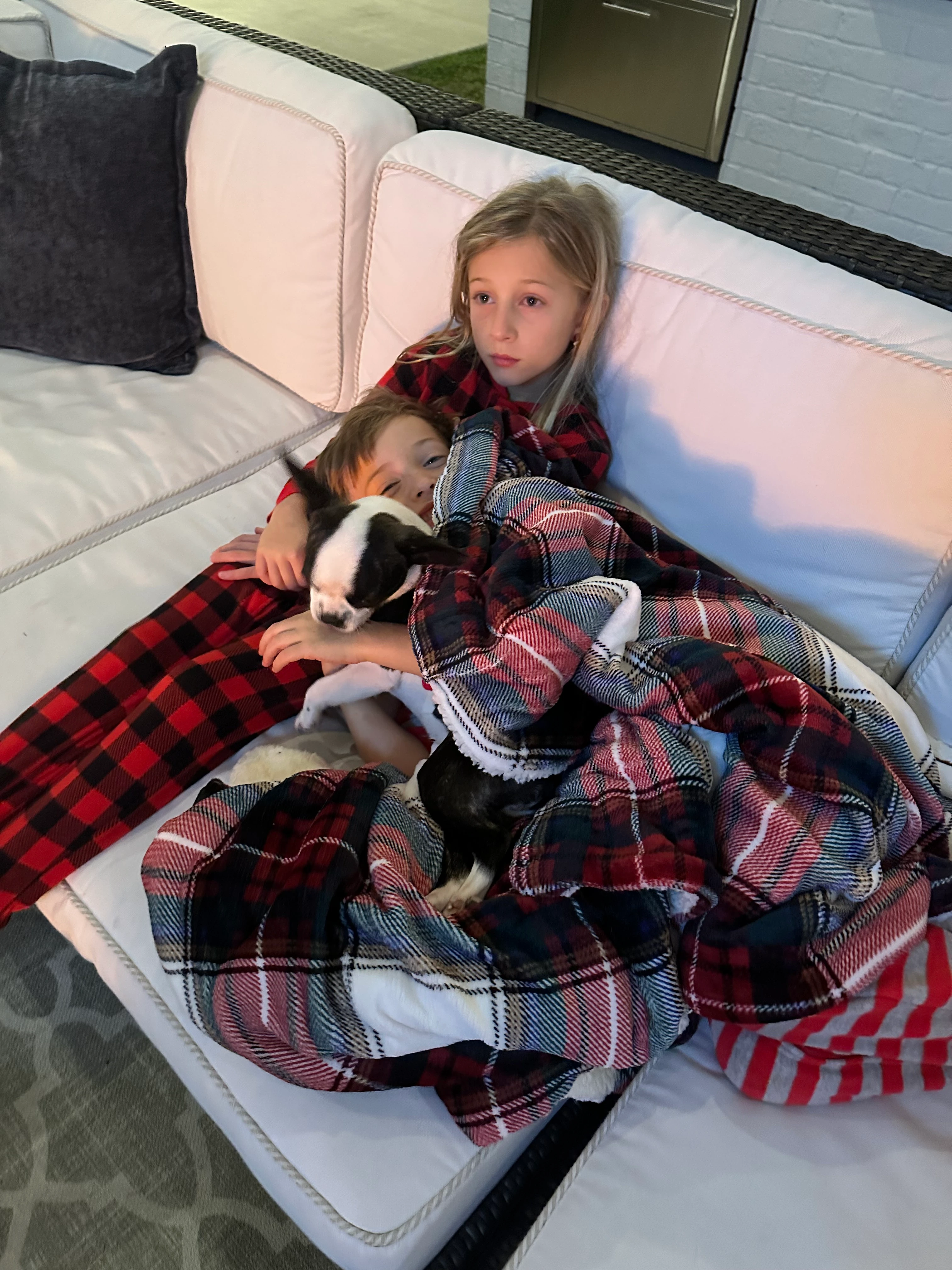 Siblings snuggling on the couch with their Royal Frenchel.