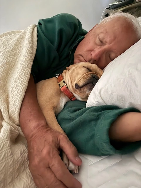 Man sleeping beside his Royal Frenchel in a peaceful snuggle.