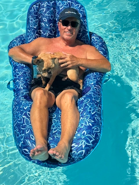 Man relaxing on a pool float with his Royal Frenchel on his lap.