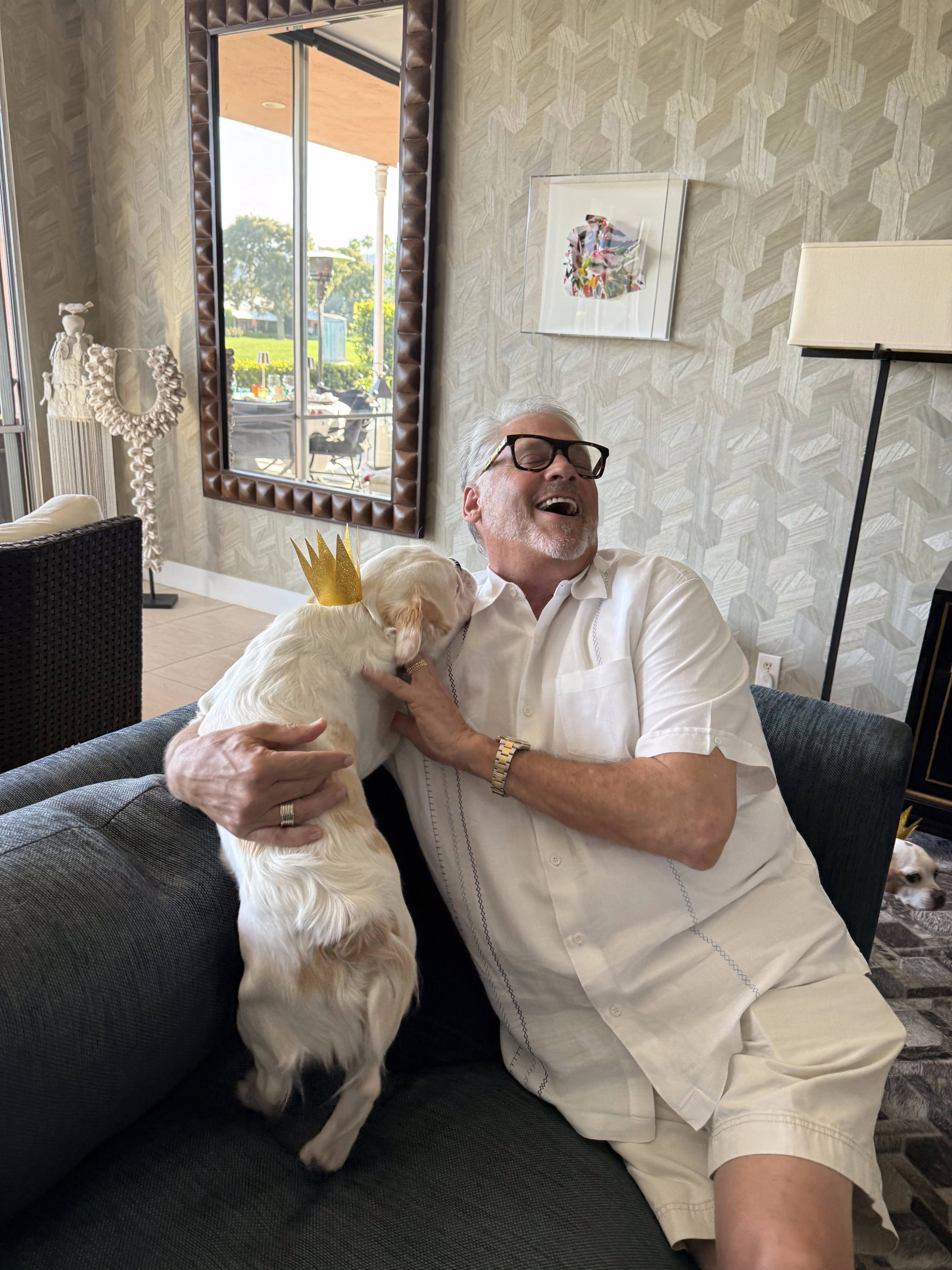 Royal Frenchel wearing a small crown while snuggling with a man on the couch.
