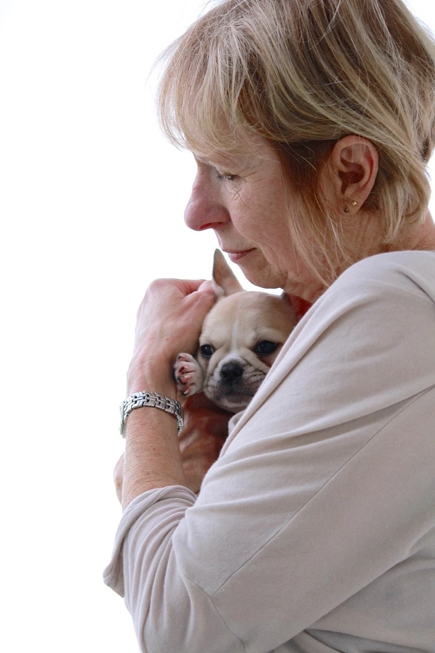 Senior woman cuddling closely with her Royal Frenchel puppy.