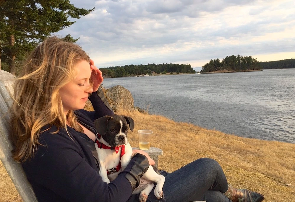 Woman sitting by the water with her Royal Frenchel on her lap.