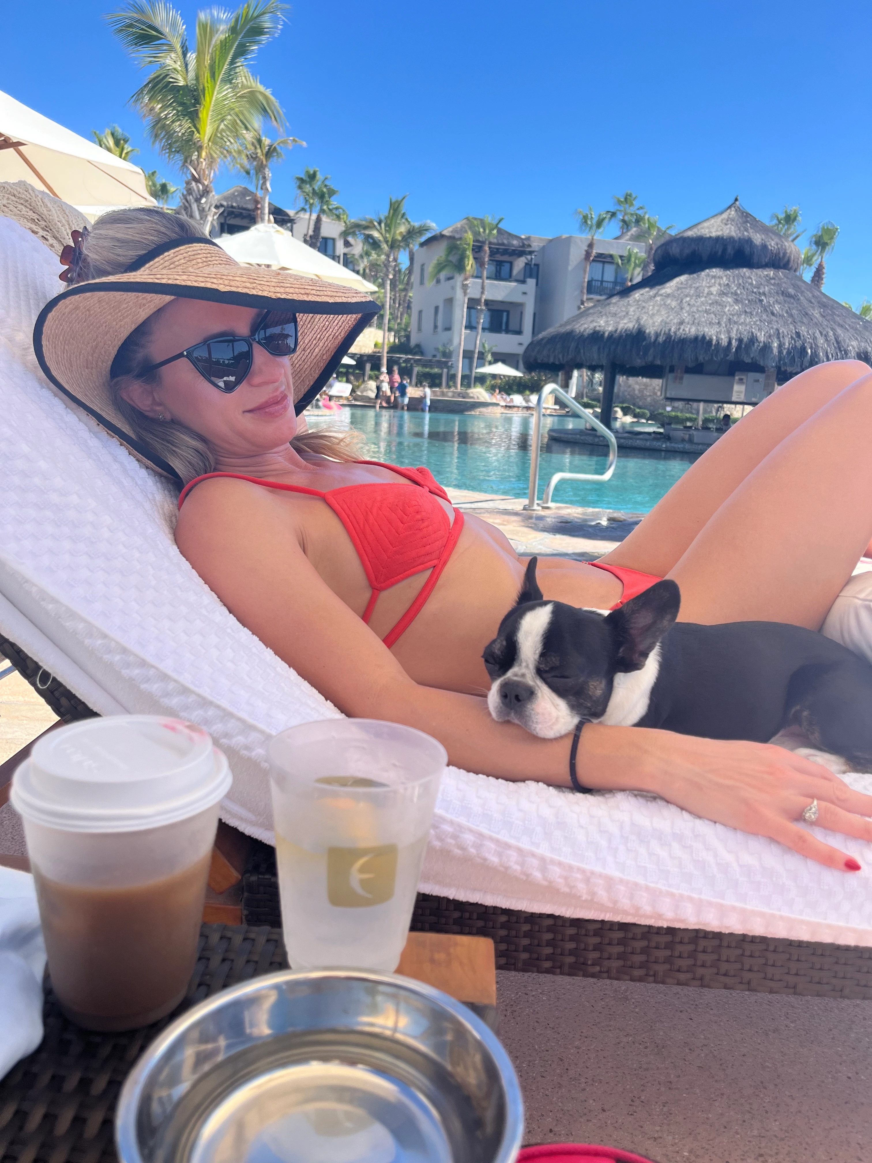 Woman relaxing on a tanning bed with her dog beside her.