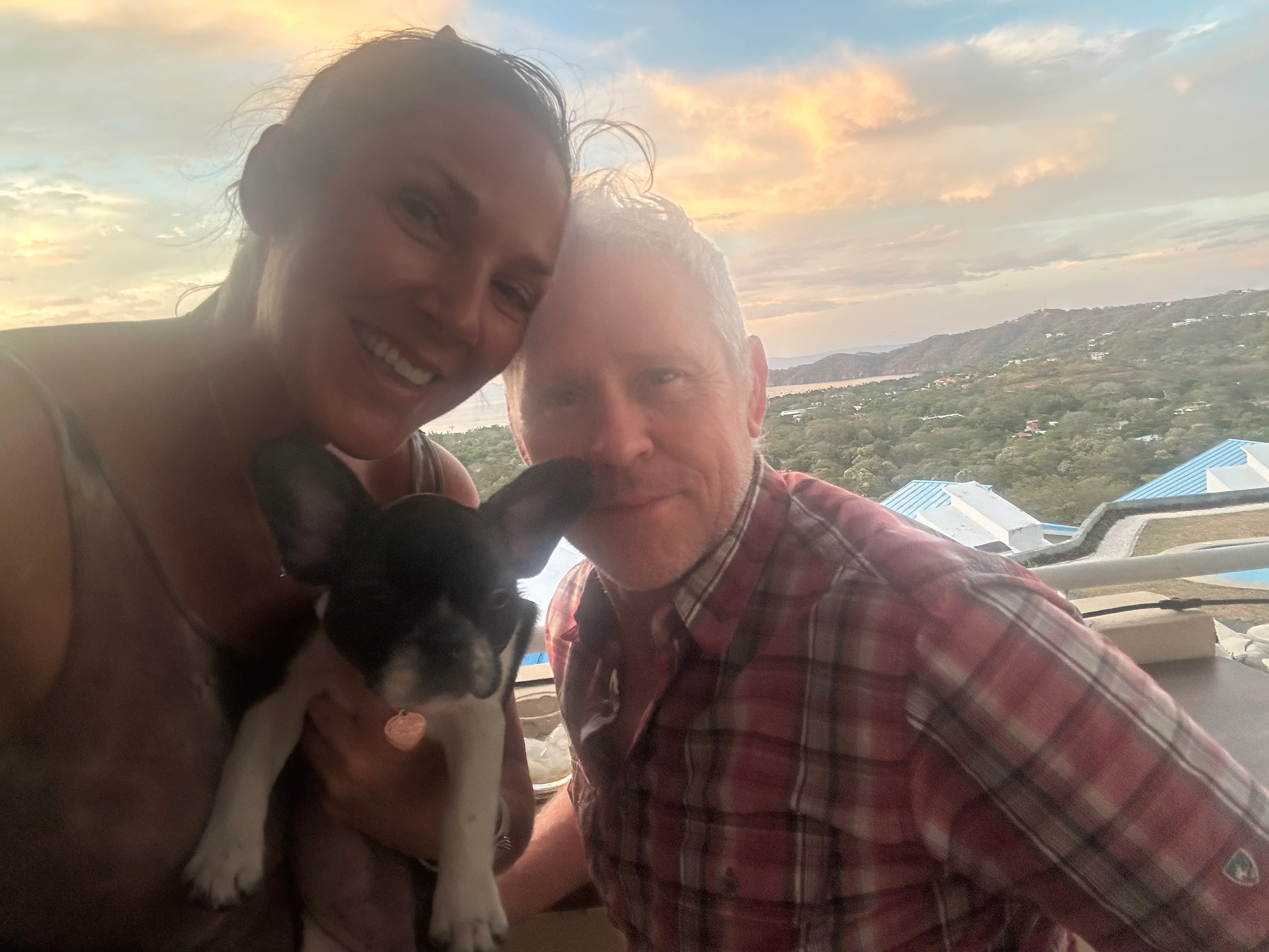 Couple holding their Royal Frenchel in front of a scenic sunset view.