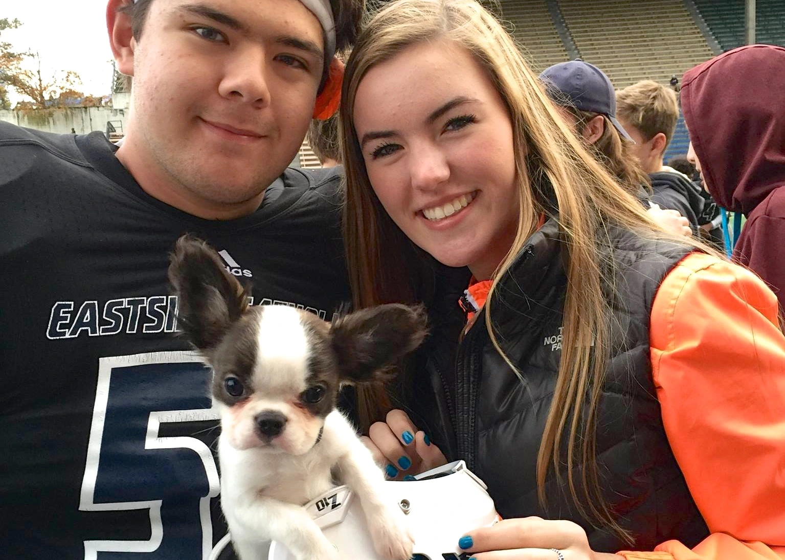 High school couple holding their Royal Frenchel puppy together.