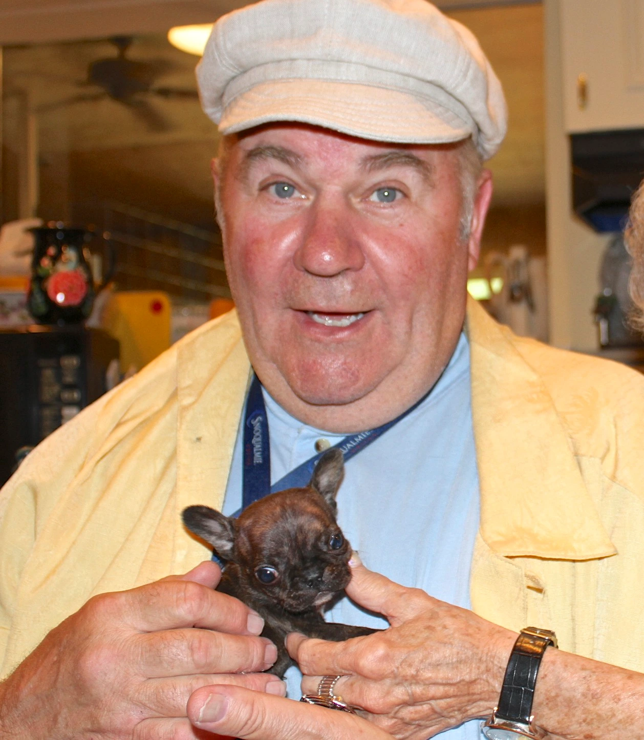 Man holding a tiny Royal Frenchel puppy close to his chest.
