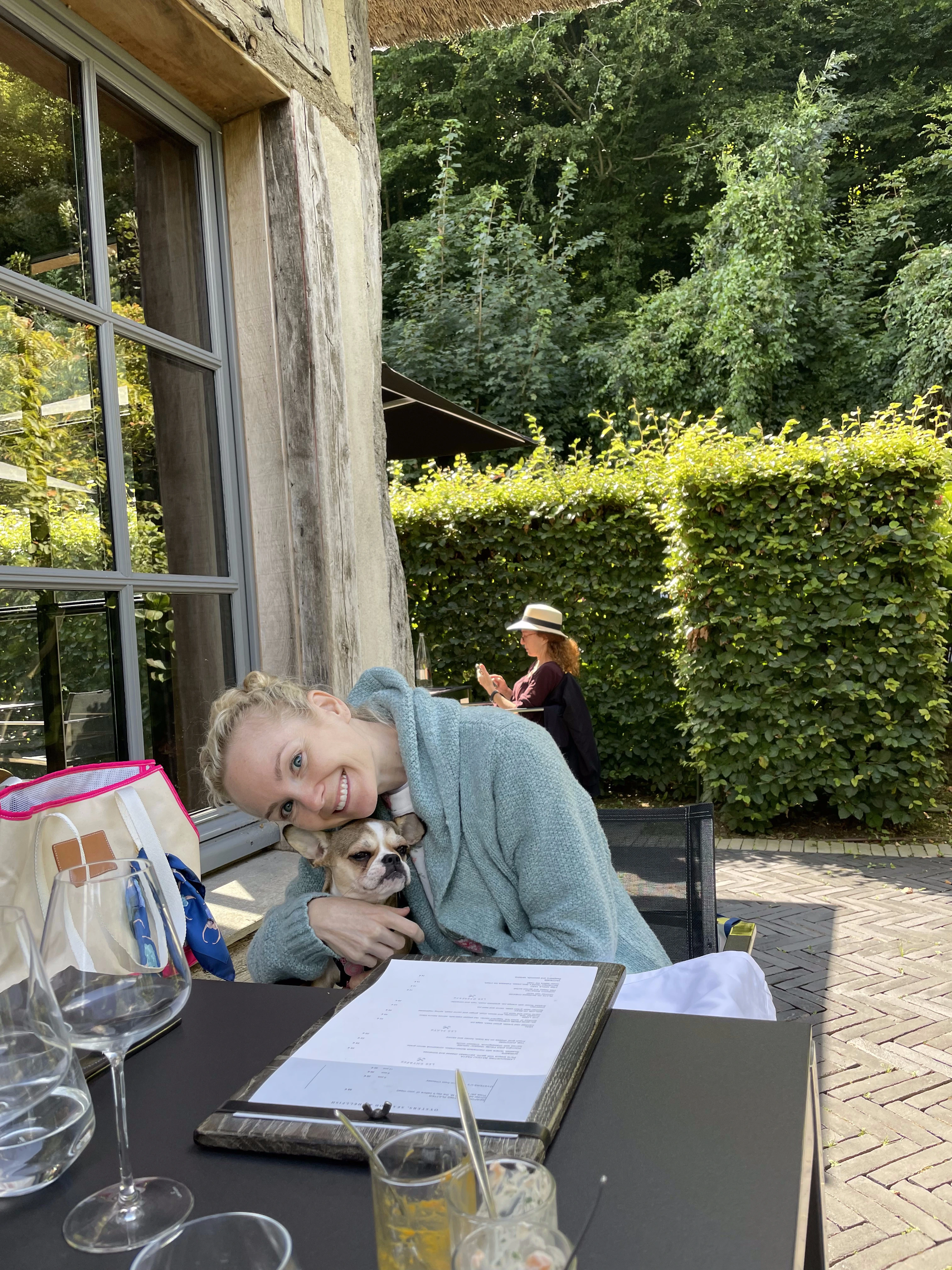 Woman sitting at a restaurant with her Royal Frenchel on her lap.