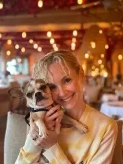 Woman smiling while cuddling a Royal Frenchel in a restaurant.